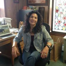 A woman is sitting in a chair in front of a desk.