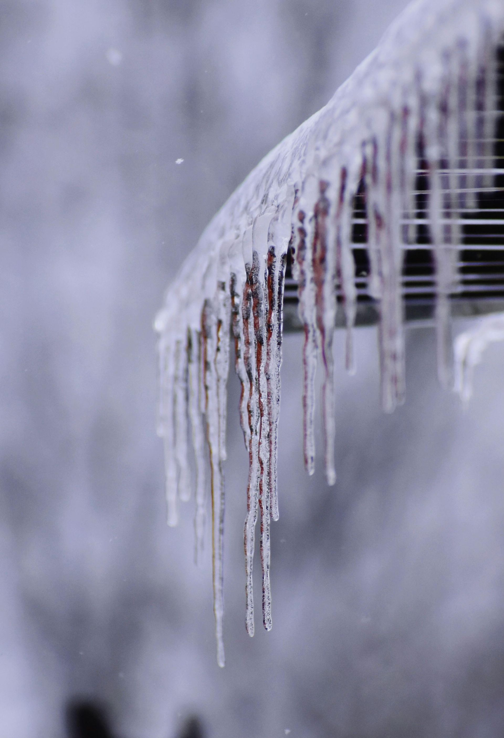 Icicles hang from a roofline during a snowfall.