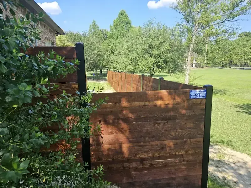 Wooden fence and gate beside a grassy field on a sunny day