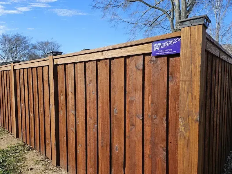 Wooden privacy fence with a purple sign, viewed from the corner on a sunny day