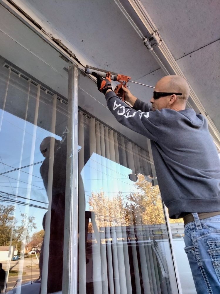 Person using a power drill to work on an awning above a large window.