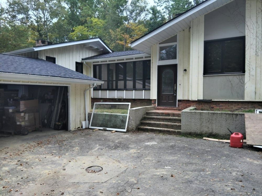 A light-colored house with a dark roof and a driveway. A garage is attached to the house.