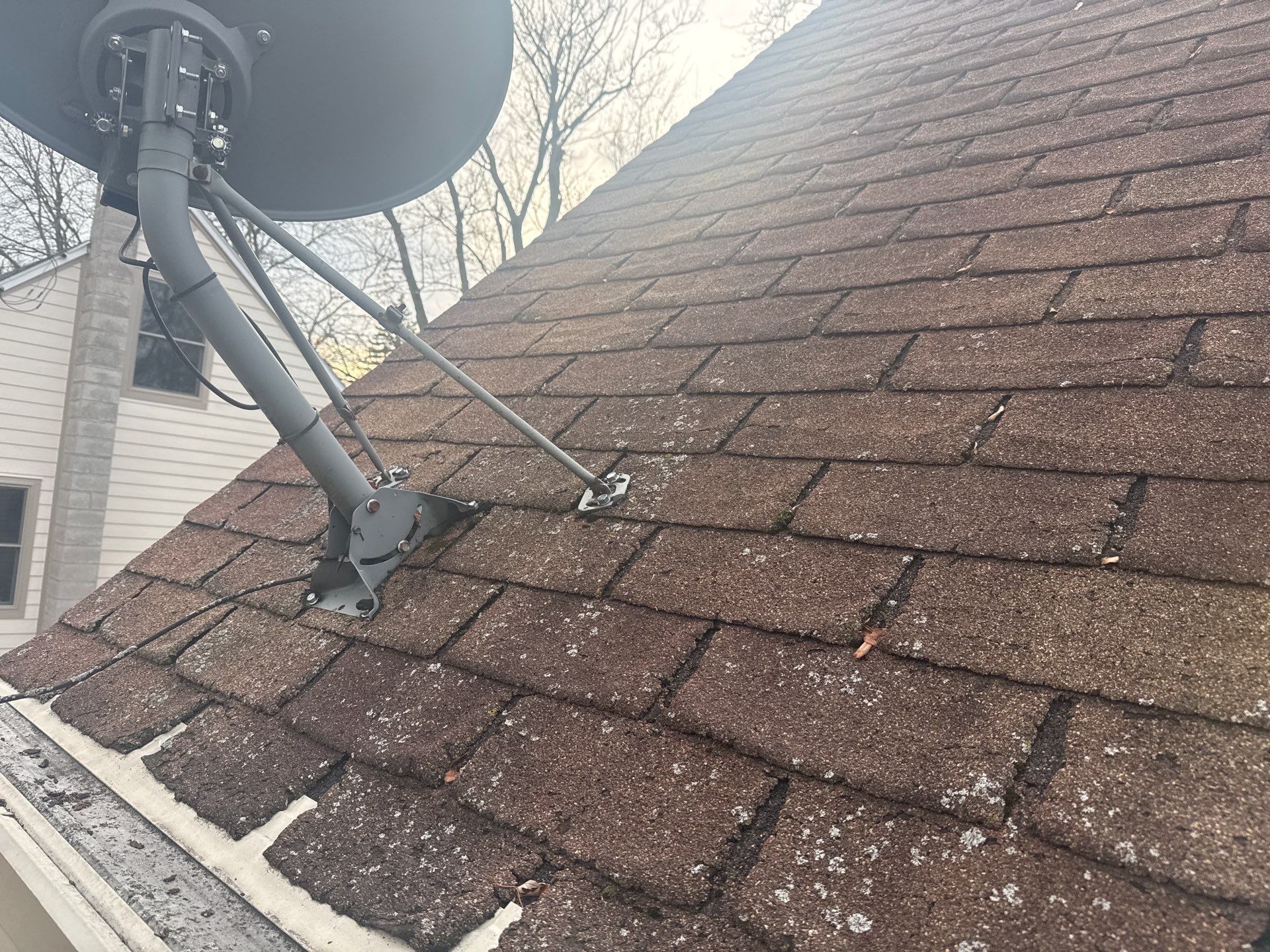 A man is installing slate tiles on a roof.