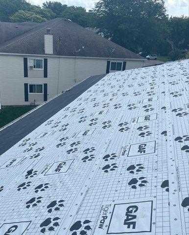 A roof with a lot of shingles on it and a house in the background.