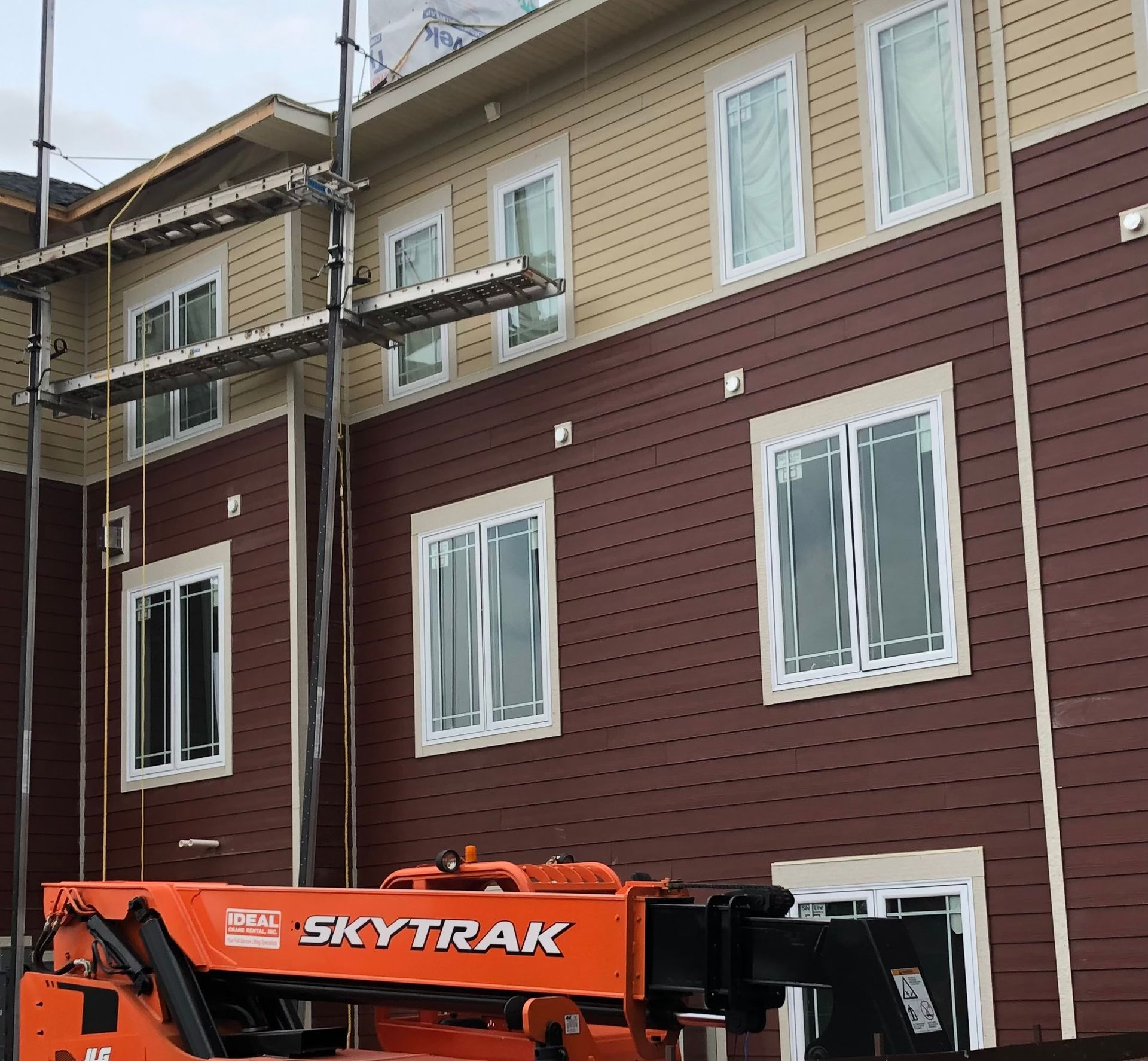 A man is standing on top of a roof holding a clipboard.
