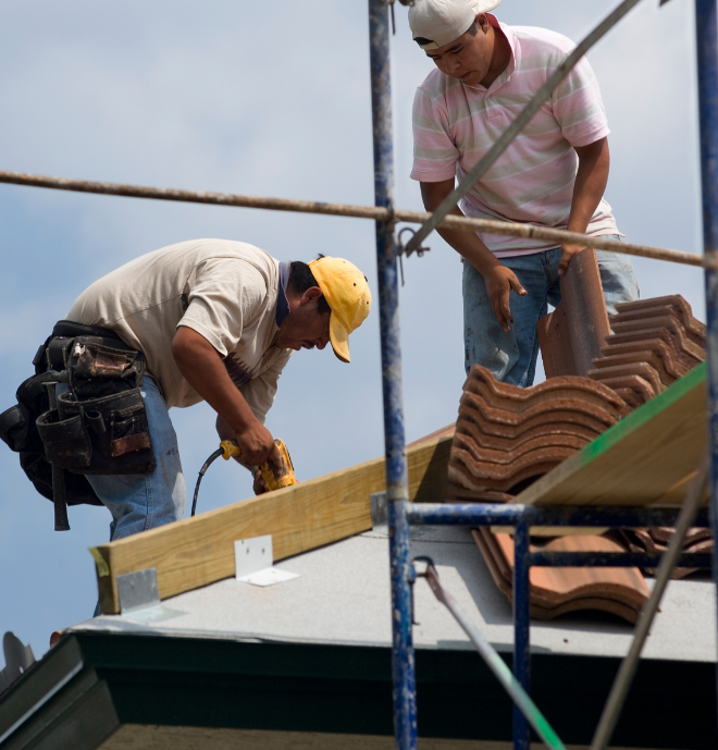 Two men are working on the roof of a building