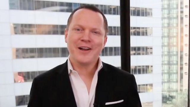 A man in a suit is standing in front of a window