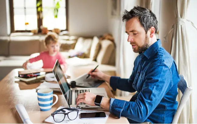 A man is sitting at a table using a laptop computer.