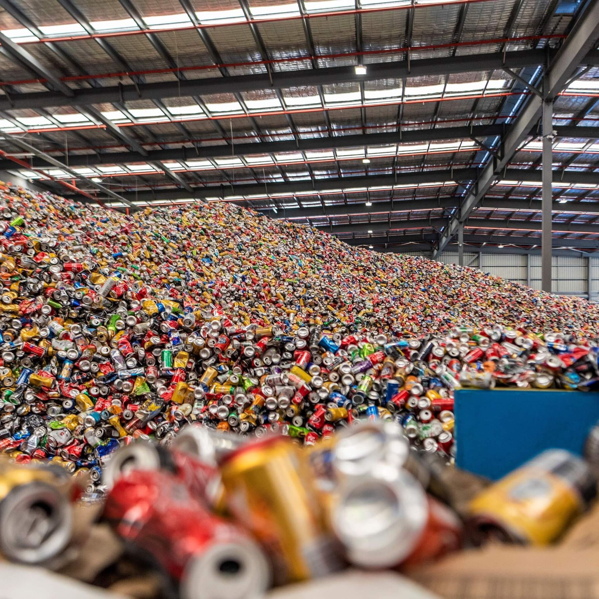 A large pile of cans and bottles in a warehouse.