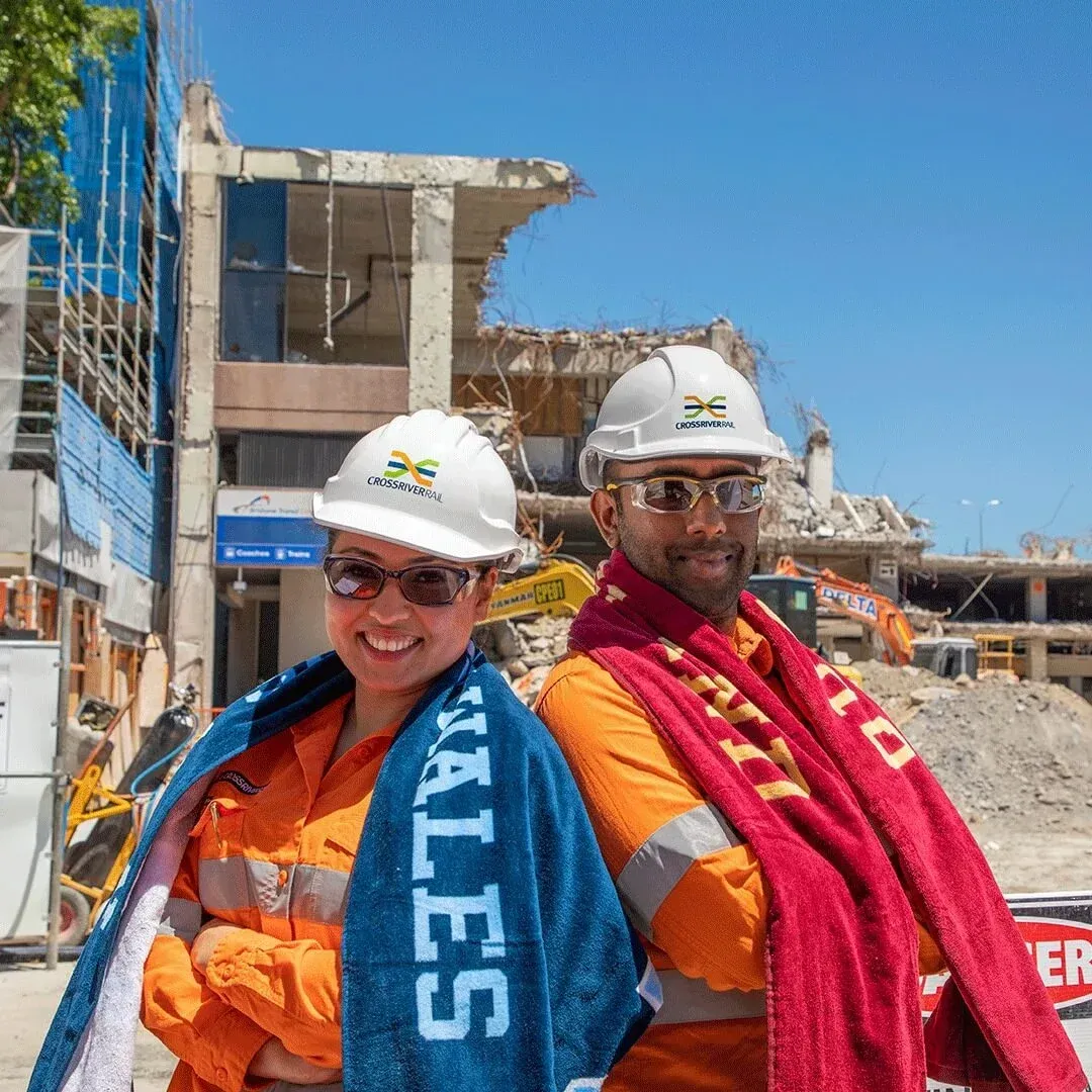 A man and a woman are posing for a picture with a towel that says tales on it.