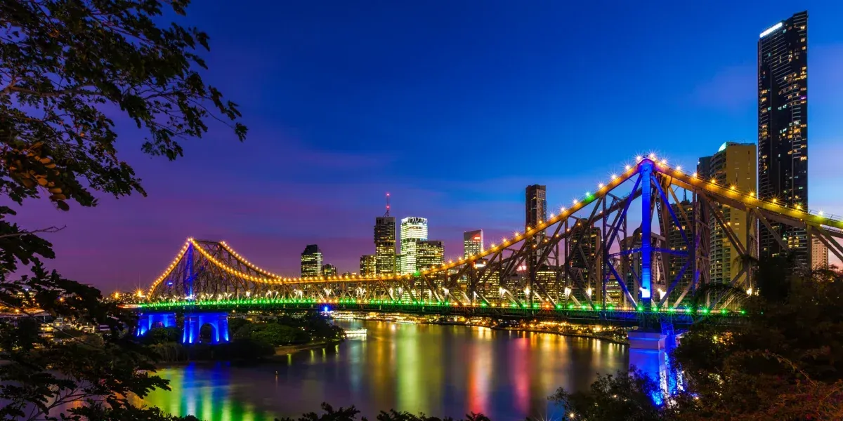A bridge over a body of water with a city in the background at night.