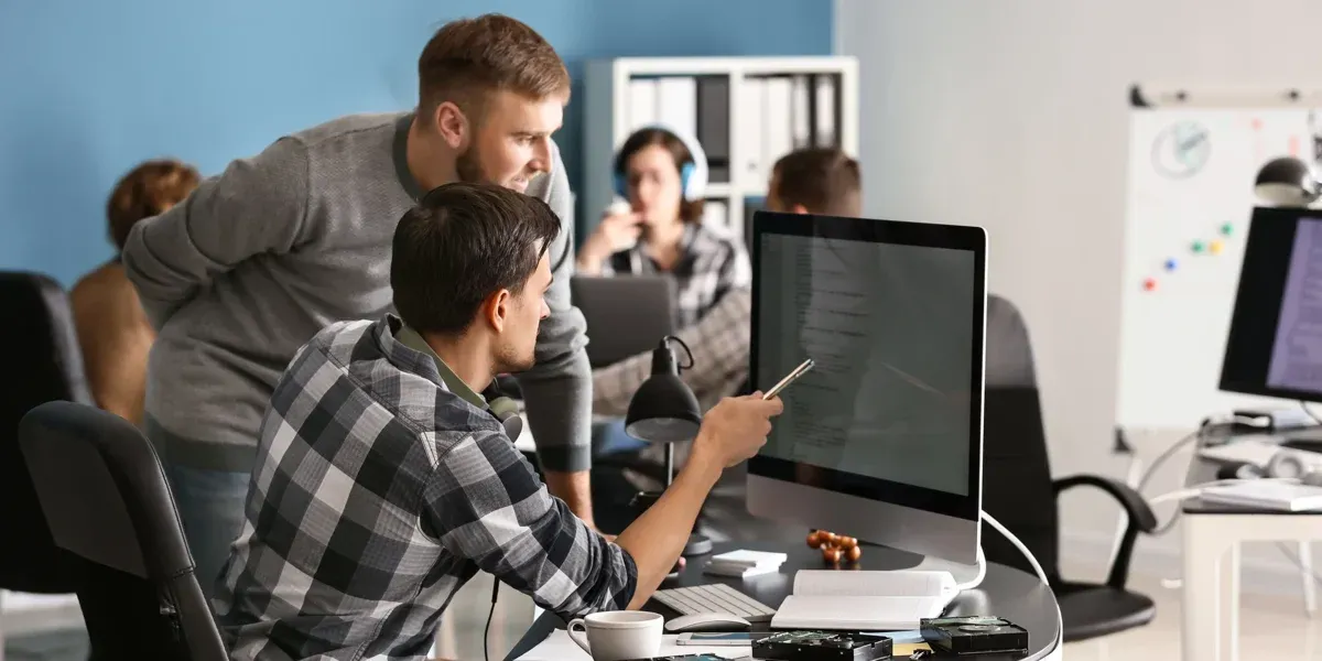 Two men are looking at a computer screen in an office.