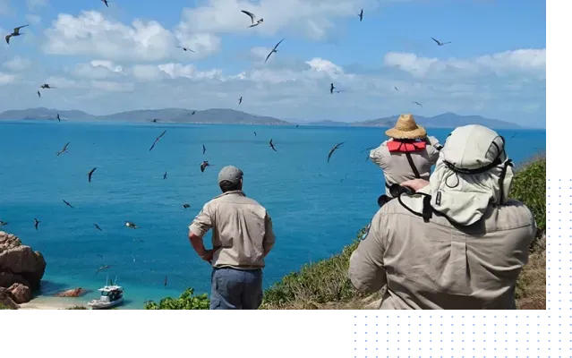 A couple of people standing on top of a hill overlooking a body of water.