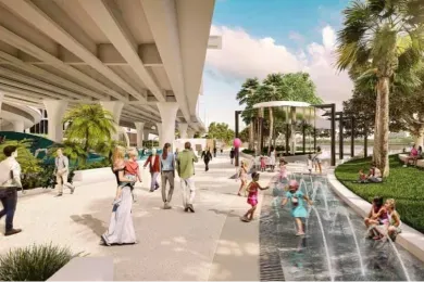 A group of people are walking down a sidewalk next to a fountain.