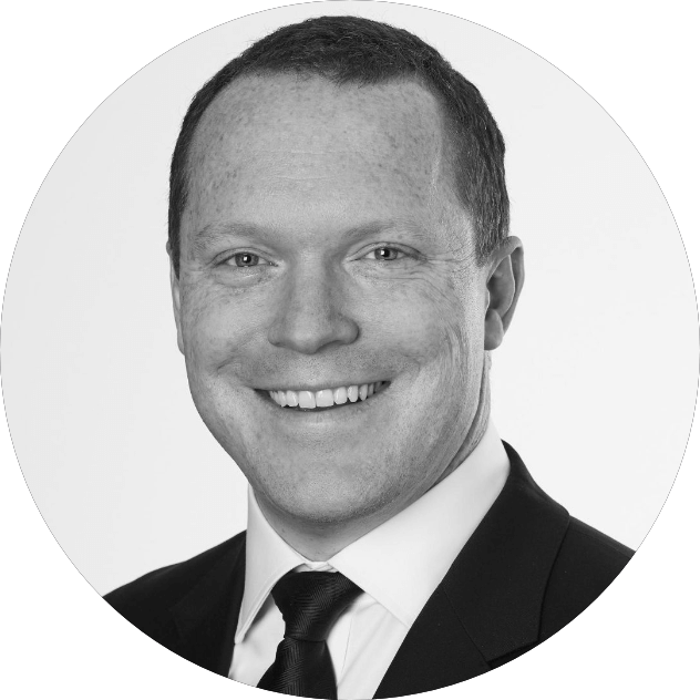 A man in a suit and tie is smiling in a black and white photo