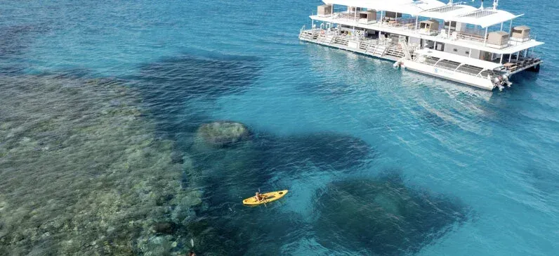 A boat is floating on top of a body of water next to a coral reef.