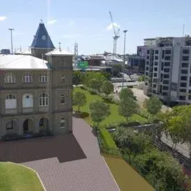 An aerial view of a large building with a clock tower in the middle of a city.