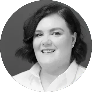 A woman in a white shirt is smiling in a black and white photo.