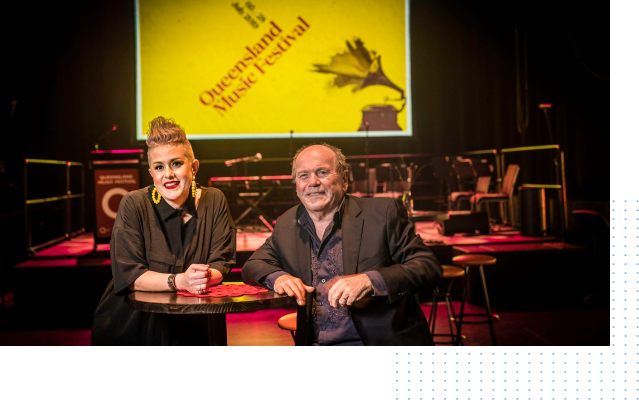 A man and a woman are sitting at a table in front of a stage.