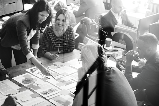 A group of people are sitting around a table looking at papers.