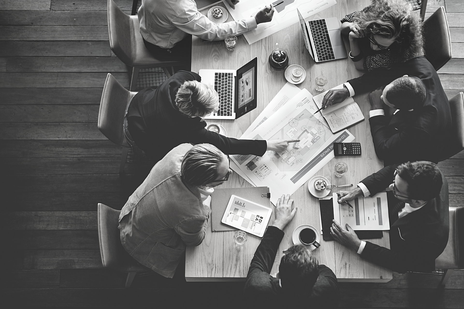 A group of people are sitting around a table with laptops.