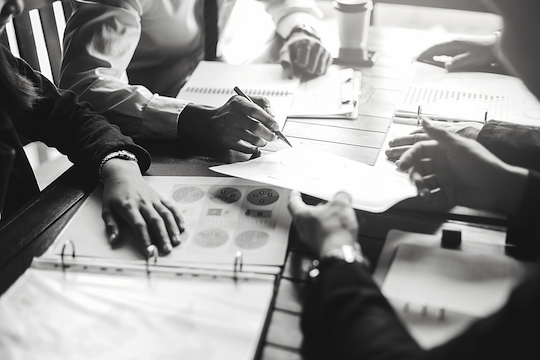 A group of people are sitting around a table looking at papers.