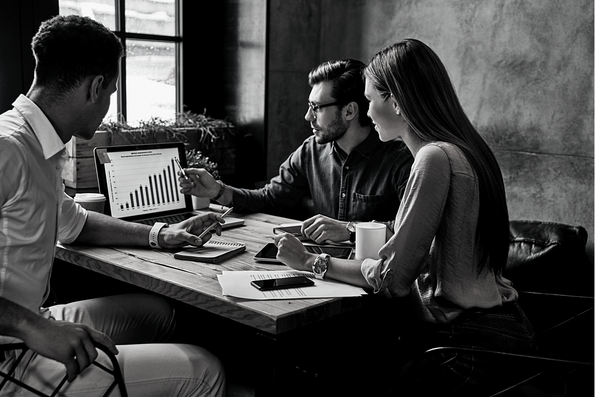 A group of people are sitting around a table looking at a laptop.