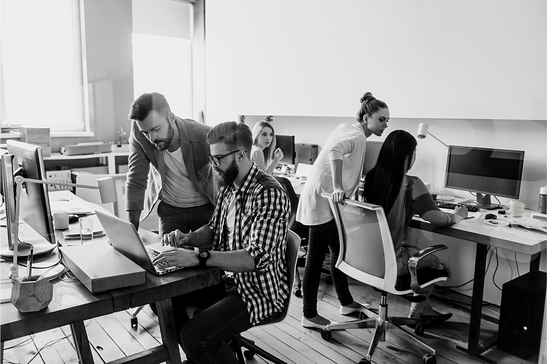 A group of people are working on a laptop computer in an office.
