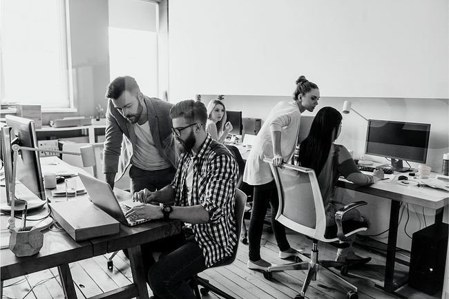 A group of people are working on a laptop computer in an office.