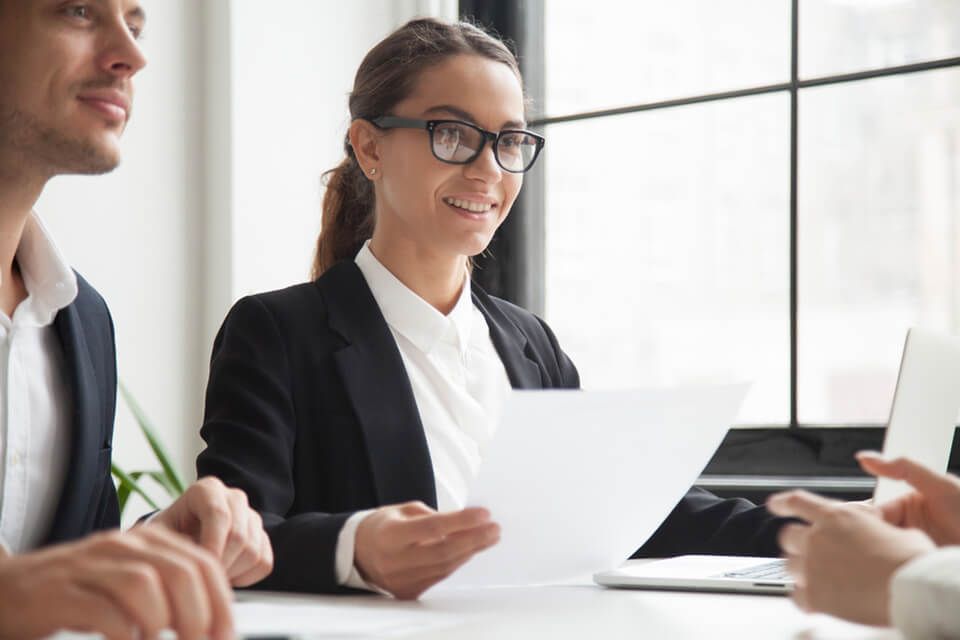 A woman is sitting at a table holding a piece of paper.