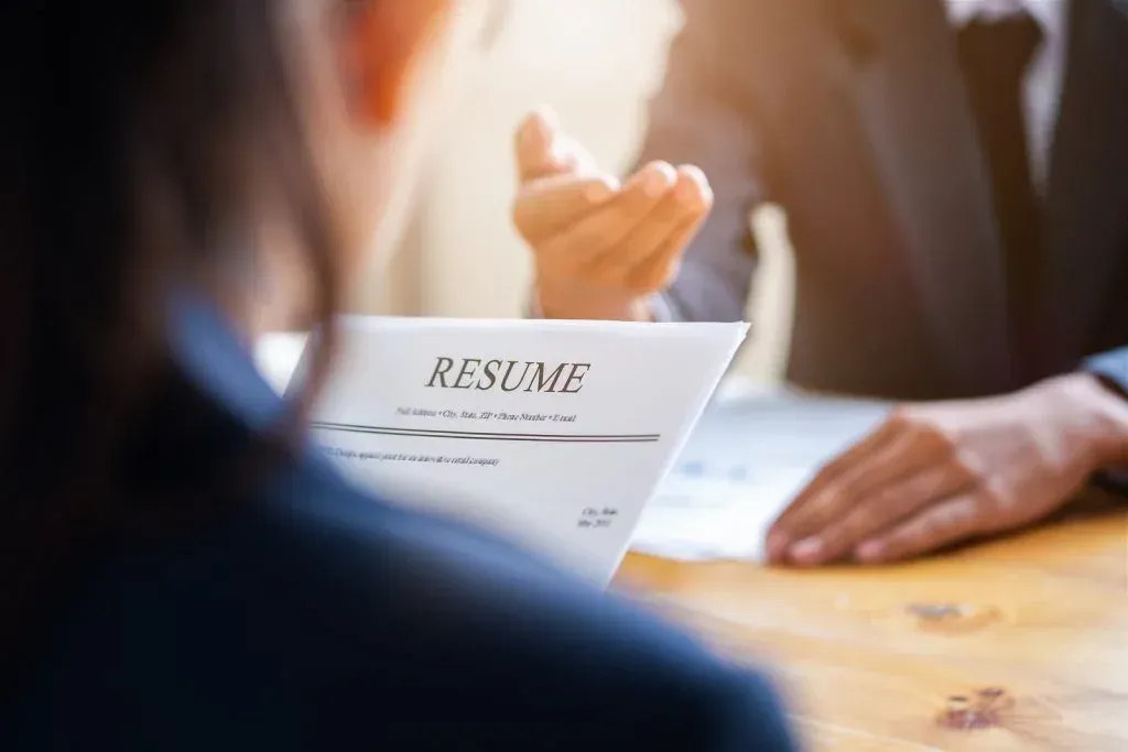 A woman is sitting at a table with a resume in front of her.