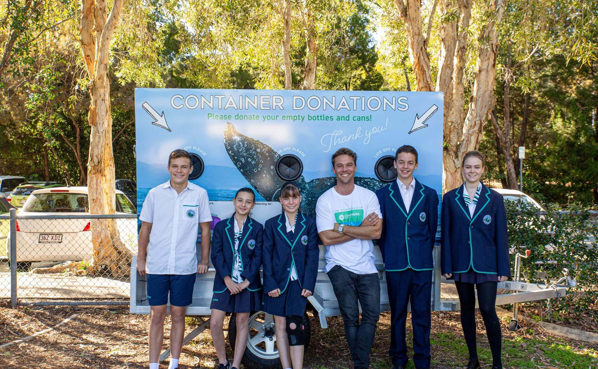A group of young people are standing in front of a sign.