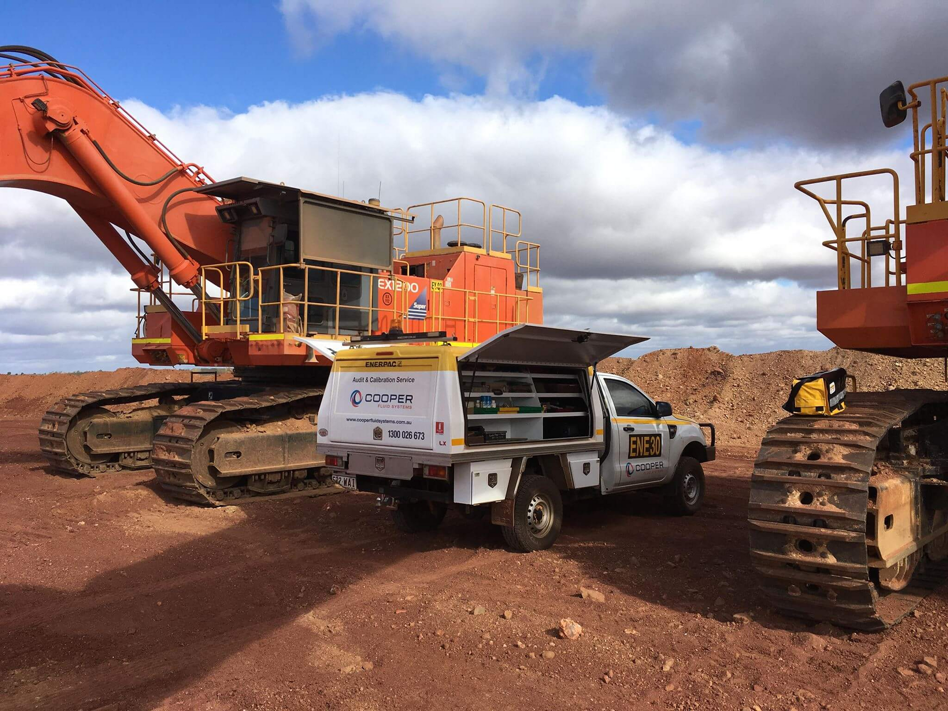 A truck is parked next to a large excavator.