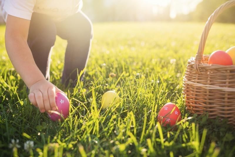 A child is picking up easter eggs in the grass.