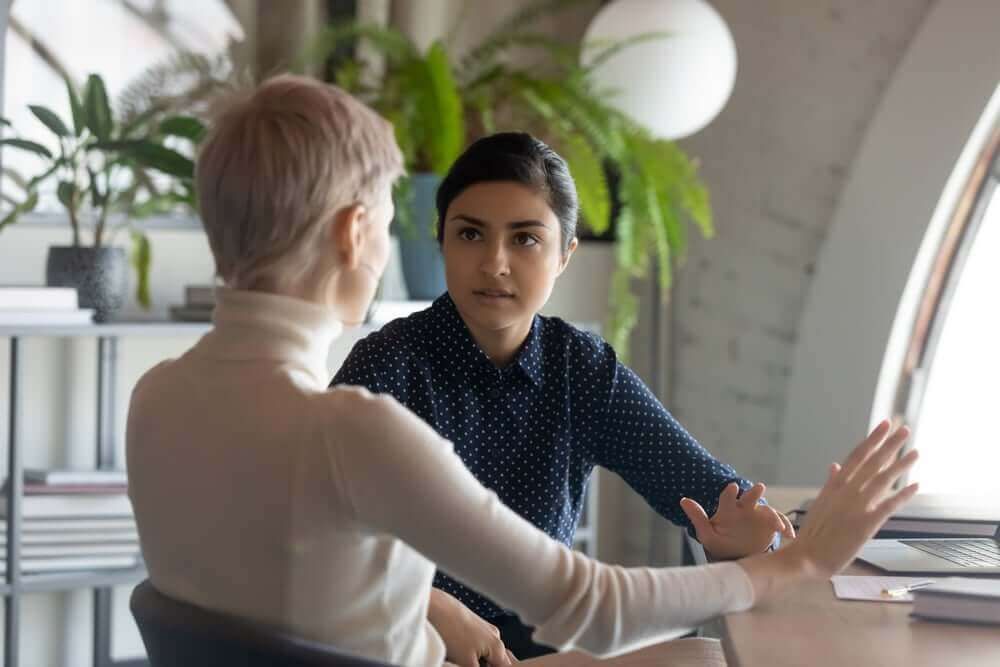 Two women are sitting at a table having a conversation.