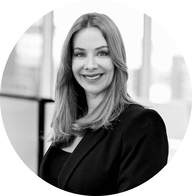 A woman in a black jacket is smiling in a black and white photo.