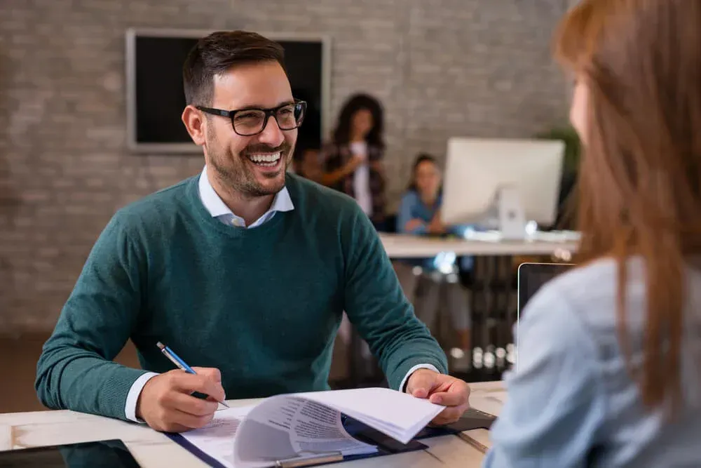A man is sitting at a table talking to a woman.
