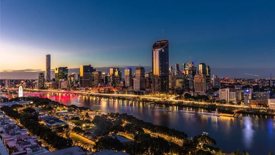 An aerial view of a city skyline at night with a river in the foreground.