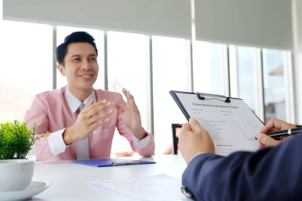 A man is sitting at a table having a job interview with another man.