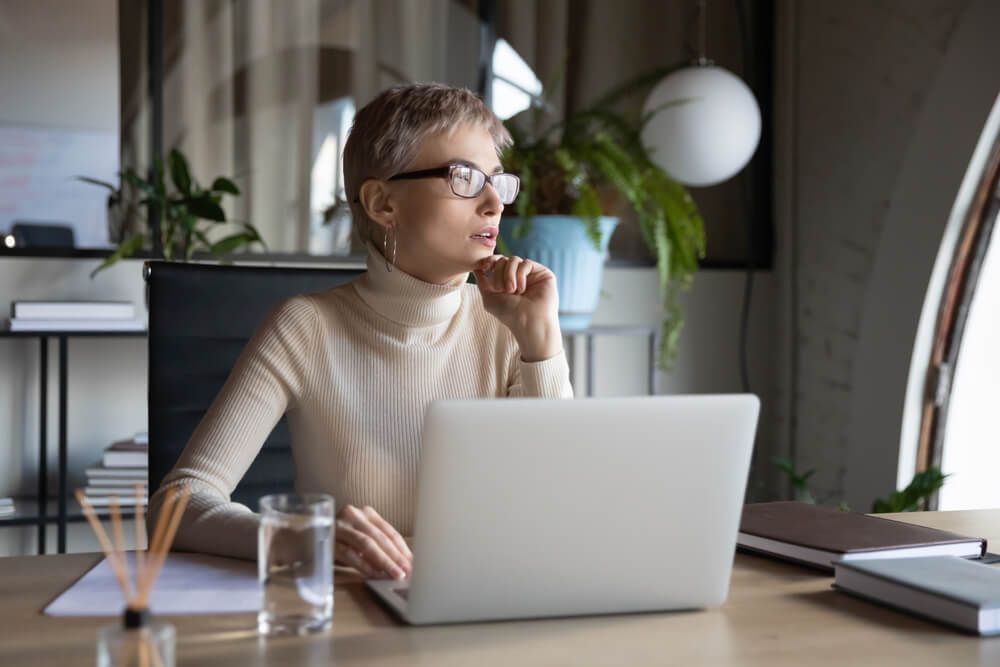 A woman is sitting at a desk using a laptop computer.