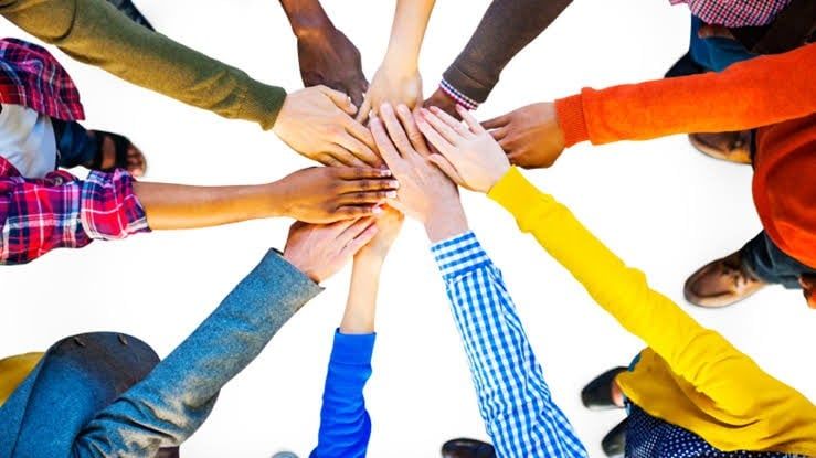 A group of people are putting their hands together in a circle.