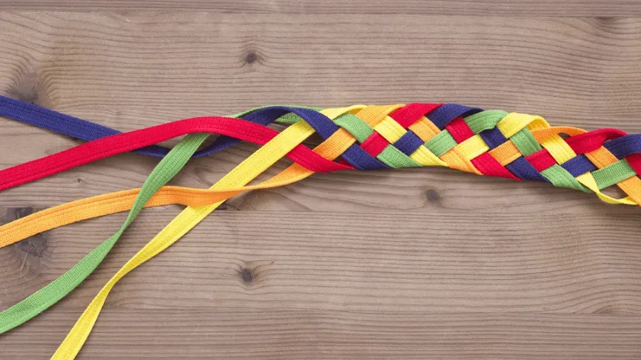 A colorful braided ribbon is sitting on a wooden table.