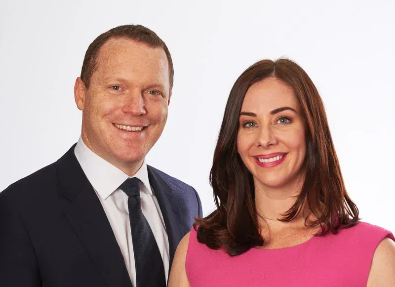 A man in a suit and tie is standing next to a woman in a pink dress.