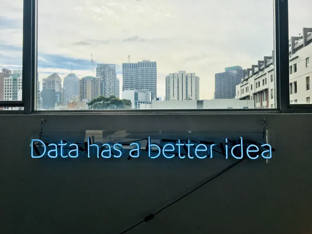 A neon sign that says `` data has a better idea '' is hanging on a wall next to a window.