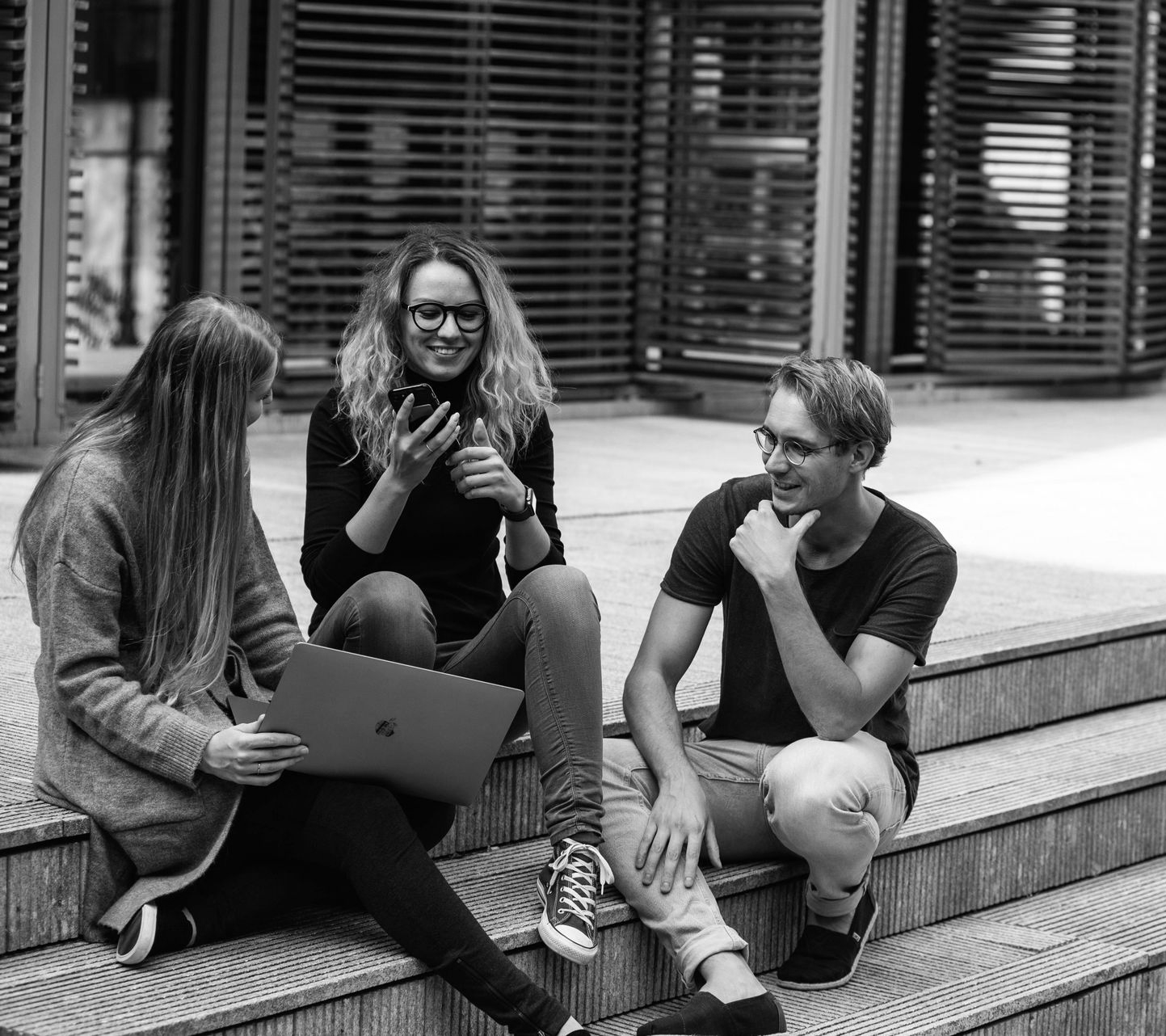 A group of people are sitting around a table looking at a laptop.