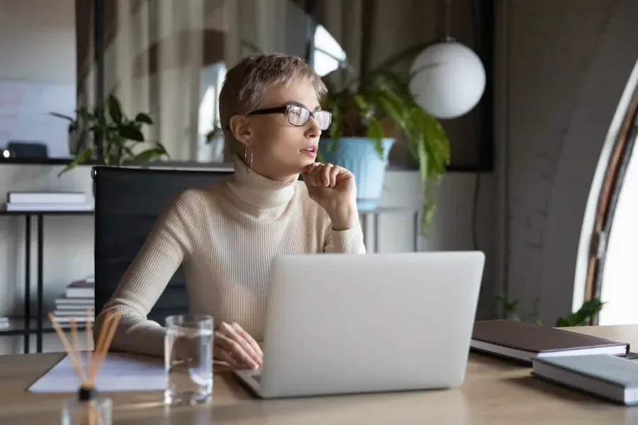 A woman is sitting at a desk using a laptop computer.