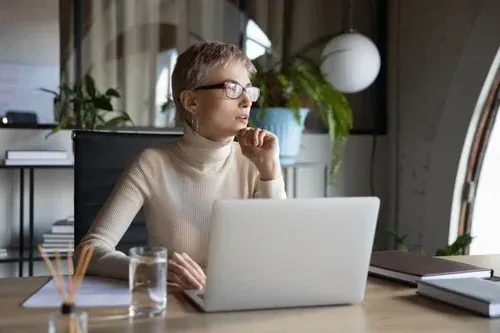 A woman is sitting at a desk using a laptop computer.