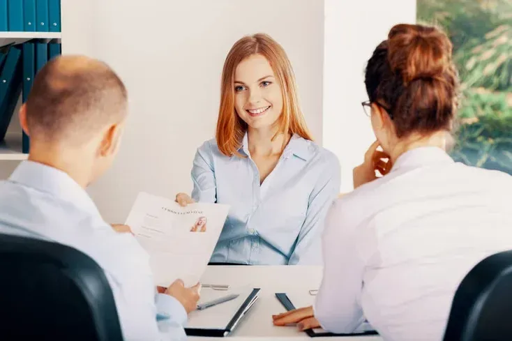 A group of people are sitting at a table having a job interview.