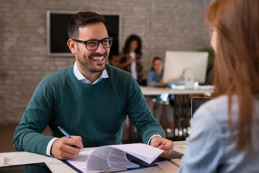 A man is sitting at a table talking to a woman.