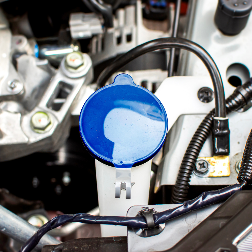 Blue windshield washer fluid reservoir cap in an engine bay.